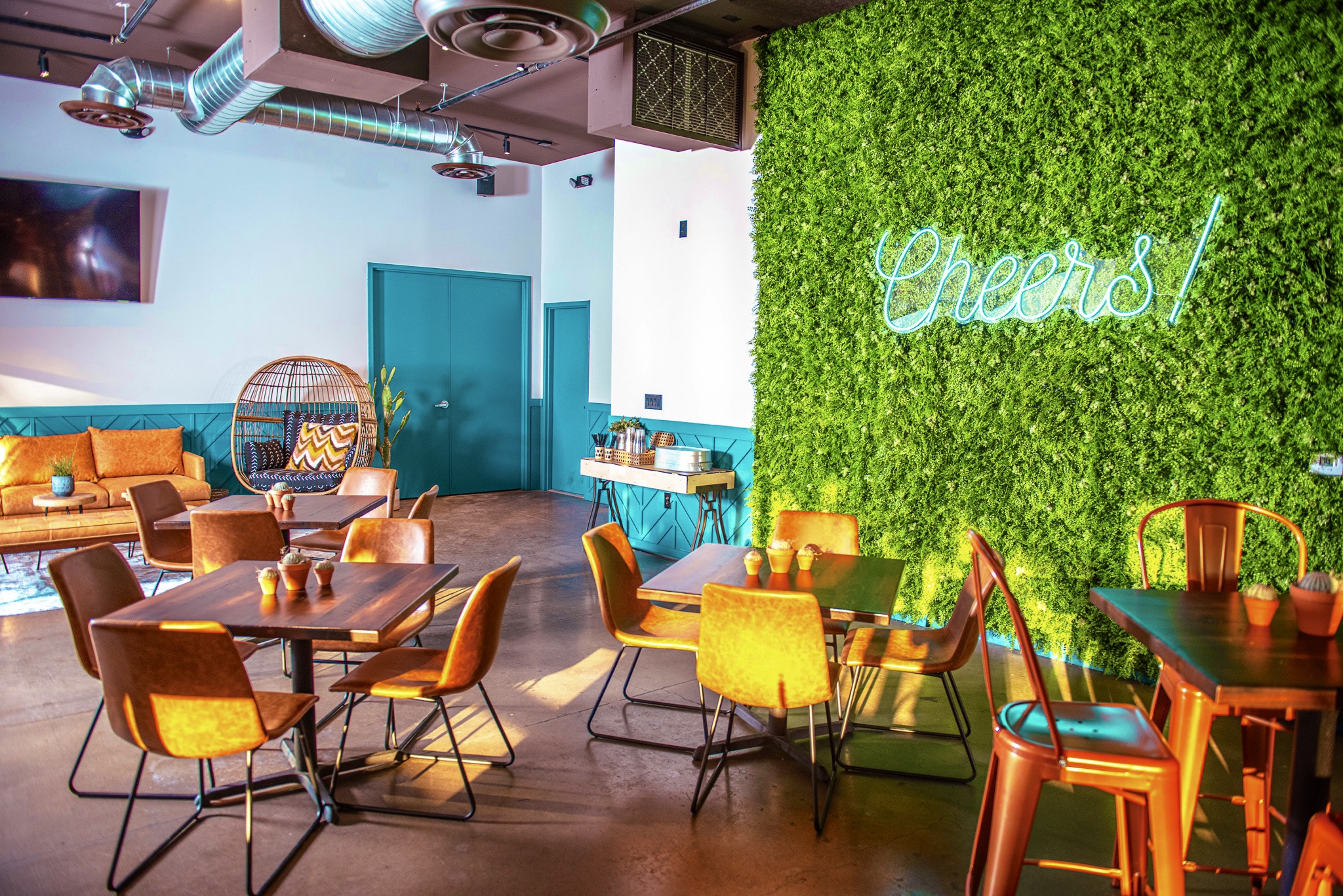 A restaurant with tables and chairs in front of a green wall.